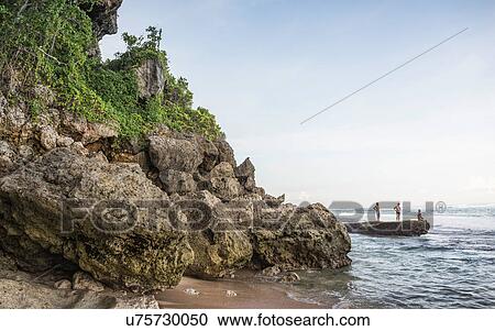 Stock Image - Three men on coastal rock at Panawa Beach, Bali, Indonesia. Fotosearch
