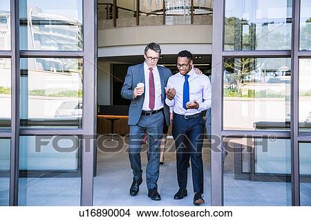 Two businessmen leaving office building View Large Photo Image Picture - Two businessmen leaving office building. Fotosearch