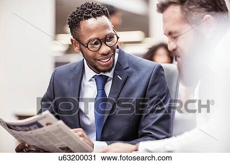 Two businessmen reading newspaper in office View Large Photo Image Stock Image - Two businessmen reading newspaper in office. Fotosearch