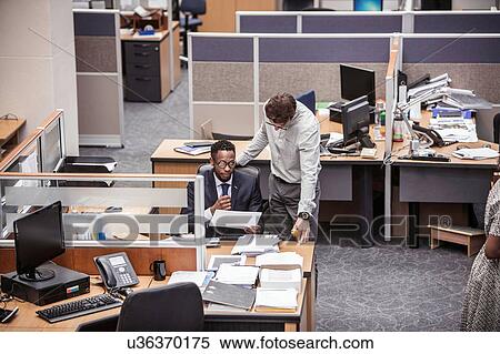 Stock Photography - Two businessmen talking at office desk. Fotosearch