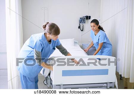 Stock Photo - Two female nurses making hospital bed in ward. Fotosearch