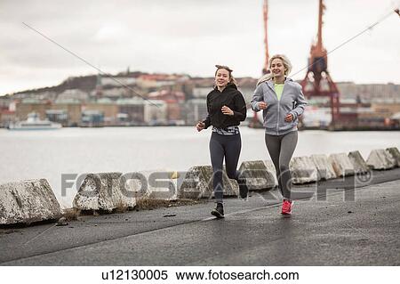 Two female runner friends running along dockside View Large Photo Image Stock Photography - Two female runner friends running along dockside. Fotosearch