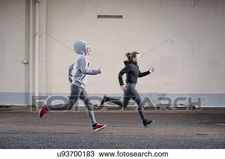 Two female runner friends running on urban road View Large Photo Image Stock Image - Two female runner friends running on urban road. Fotosearch
