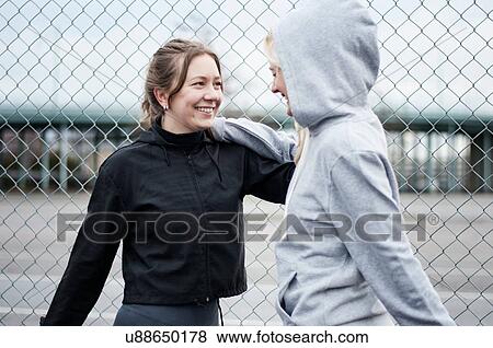 Stock Photo - Two female runners warming up by wire fence. Fotosearch