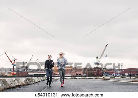 Two female running friends running along dockside View Large Photo Image Stock Image - Two female running friends running along dockside. Fotosearch