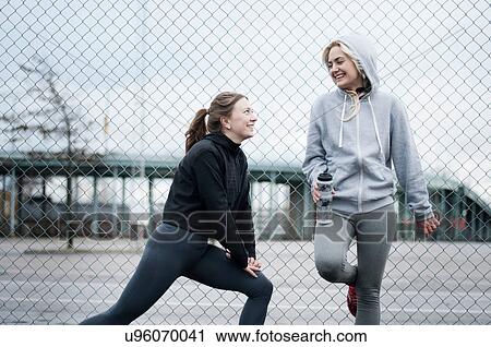 Two female running friends warming up by wire fence View Large Photo Image Stock Image - Two female running friends warming up by wire fence. Fotosearch