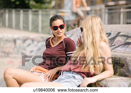 Two female skateboarding friends chatting in skatepark View Large Photo Image Stock Photograph - Two female skateboarding friends chatting in skatepark. Fotosearch