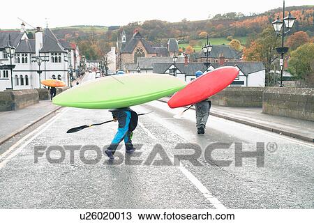 Stock Image - Two kayakers carrying kayaks on bridge over River Dee, Llangollen, North Wales. Fotosearch