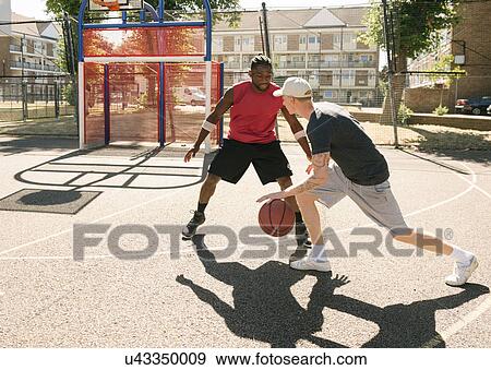 Stock Photo - Two male basketball players practising on basketball court. Fotosearch