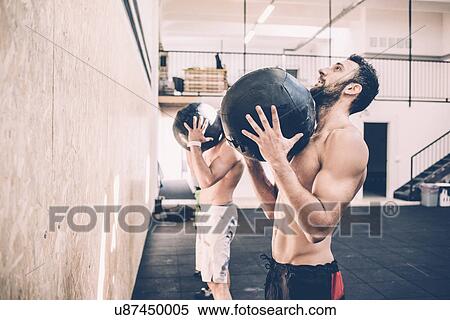 Stock Photography - Two male cross trainers holding exercise balls in gym. Fotosearch