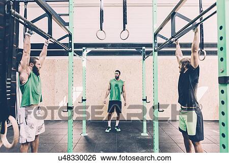 Stock Photograph - Two male cross trainers training on exercise bar in gym. Fotosearch