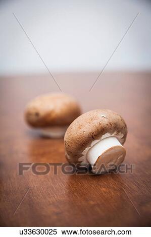 Stock Photography - Two mushrooms on wooden table. Fotosearch