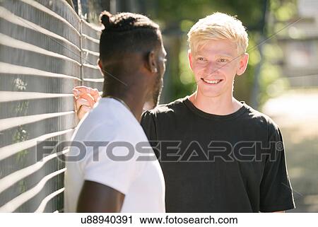 Two young men chatting by wire fence View Large Photo Image Stock Image - Two young men chatting by wire fence. Fotosearch