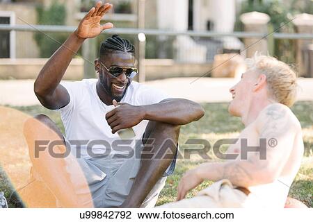 Two young men high fiving each other in park View Large Photo Image Stock Image - Two young men high fiving each other in park. Fotosearch