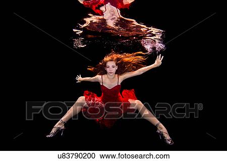 Stock Image - Underwater view of girl wearing red dress and high heeled shoes. Fotosearch