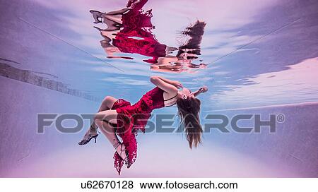 Underwater view of girl wearing red dress and high heeled shoes, floating towards water surface View Large Photo Image Stock Photo - Underwater view of girl wearing red dress and high heeled shoes, floating towards water surface. Fotosearch