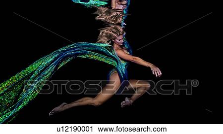 Stock Image - Underwater view of woman draped in colourful fabric. Fotosearch