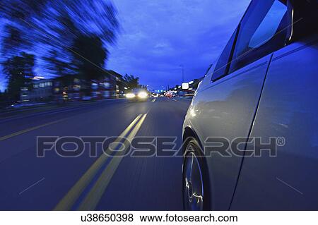 Stock Photo - USA, Colorado, Denver, Car on city street at dusk. Fotosearch