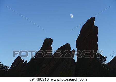 Stock Image - USA, Colorado, Moon over silhouette of rocks in Roxborough State Park. Fotosearch