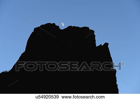 Stock Photo - USA, Colorado, Moon over silhouette of rocks in Roxborough State Park. Fotosearch