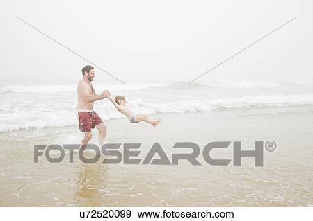 USA, New York, Monatuk, Father spinning daughter (2-3) on beach by ocean View Large Photo Image Stock Photo - USA, New York, Monatuk, Father spinning daughter (2-3) on beach by ocean. Fotosearch