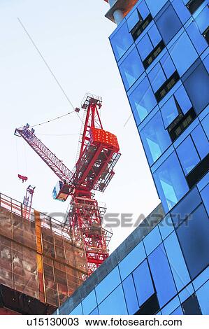 Stock Image - USA, New York, New York City, Office building with crane in background. Fotosearch