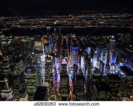 Stock Image - USA, New York, New York City, Manhattan, Aerial view of illuminated skyline with Times Square at night. Fotosearch