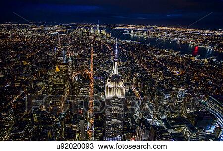 Stock Image - USA, New York, New York City, Manhattan, Aerial view of illuminated skyline at night. Fotosearch