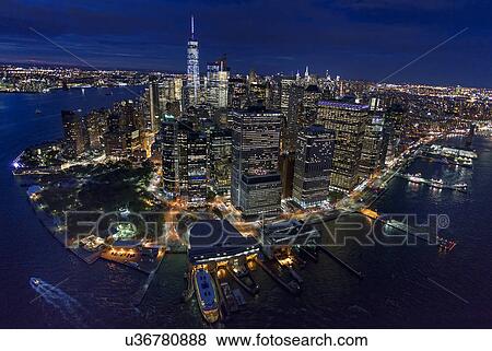 Stock Photo - USA, New York, New York City, Manhattan, Aerial view of illuminated skyline with harbor at night. Fotosearch