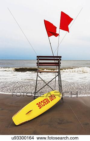 Picture - USA, New York State, New York City, Brooklyn, Yellow surfboard and empty lifeguard stand on beach. Fotosearch