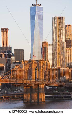 Stock Image - USA, New York State, New York City, Manhattan, Cityscape with Brooklyn Bridge at sunrise. Fotosearch