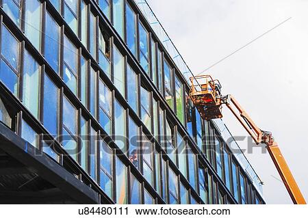 Stock Image - USA, New York State, New York City, Manhattan, Window washer cleaning office building. Fotosearch