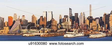 Stock Image - USA, New York State, New York City, Waterfront skyline at sunrise. Fotosearch
