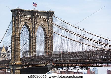 Stock Photography - USA, New York State, New York City, Brooklyn Bridge with American flag on top. Fotosearch