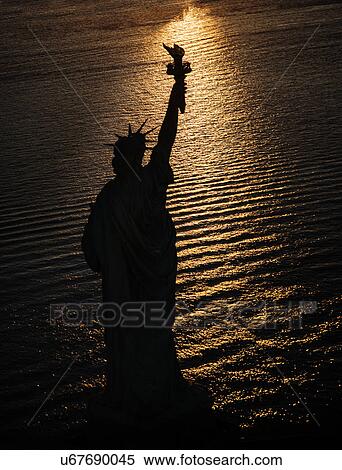 Stock Photography - USA, New York State, New York City, Silhouette of Statue of Liberty at sunrise. Fotosearch