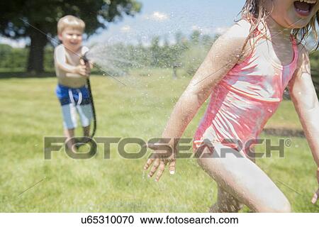 USA, Pennsylvania, Washington Crossing, Boy (4-5) and girl (2-3) playing with water hose View Large Photo Image Stock Image - USA, Pennsylvania, Washington Crossing, Boy (4-5) and girl (2-3) playing with water hose. Fotosearch