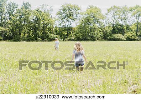 Stock Photo - USA, Pennsylvania, Washington Crossing, Children (2-3, 4-5) walking on green field. Fotosearch