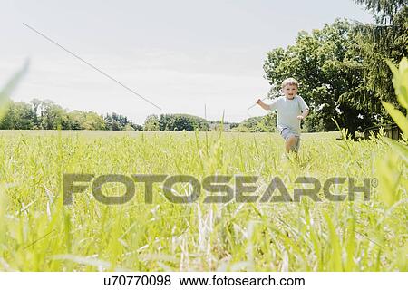 Stock Photo - USA, Pennsylvania, Washington Crossing, Boy (4-5) running in green field. Fotosearch