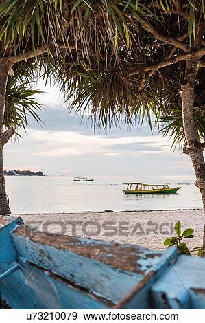 Stock Photo - View of sea and boats between trees, Gili Meno, Lombok, Indonesia. Fotosearch