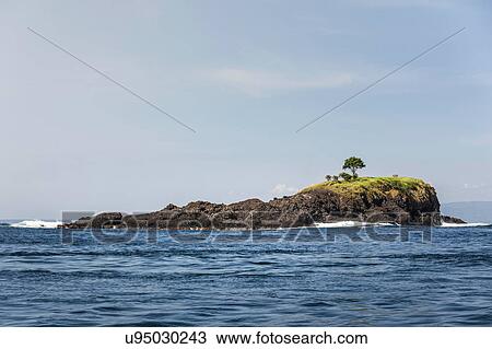 Stock Image - View of sea and rock island, Bali, Indonesia. Fotosearch