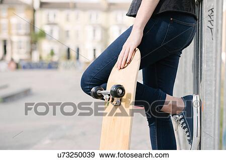 Waist down of female skateboarder leaning against fence in skatepark View Large Photo Image Stock Photo - Waist down of female skateboarder leaning against fence in skatepark. Fotosearch