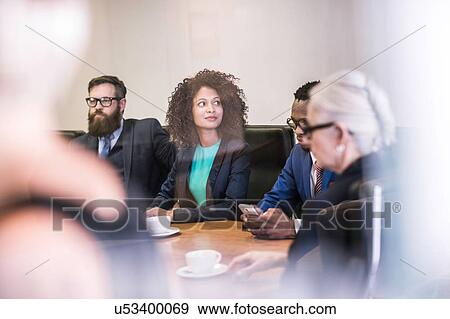 Stock Photo - Window view of businesswoman and businessmen in board meeting. Fotosearch
