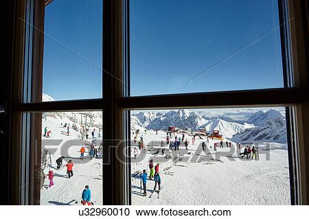 Stock Image - Window view of crowds of ski tourists on mountainside, Zugspitze, Bayern, Germany. Fotosearch
