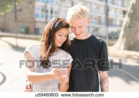 Woman and boyfriend reading smartphone update on basketball court View Large Photo Image Stock Image - Woman and boyfriend reading smartphone update on basketball court. Fotosearch