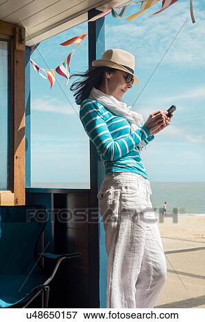 Woman at beach using smartphone View Large Photo Image Stock Photo - Woman at beach using smartphone. Fotosearch