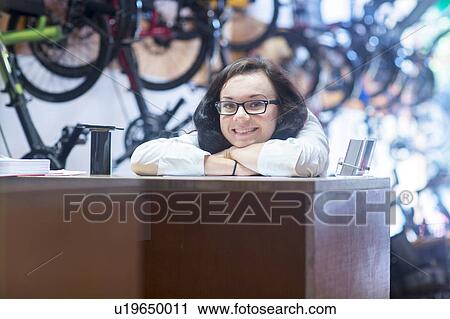 Woman at counter in bicycle shop looking at camera smiling View Large Photo Image Stock Image - Woman at counter in bicycle shop looking at camera smiling. Fotosearch
