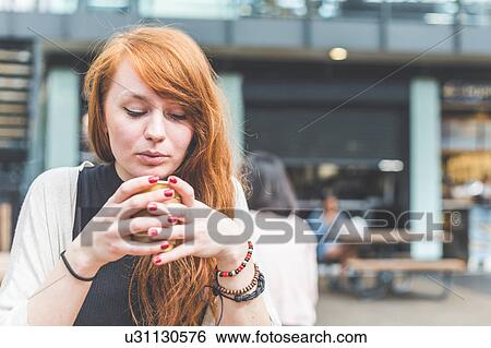 Stock Photograph - Woman at pavement cafe blowing on hot beverage, London, UK. Fotosearch