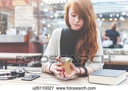 Stock Photo - Woman at pavement cafe holding disposable cup, London, UK. Fotosearch