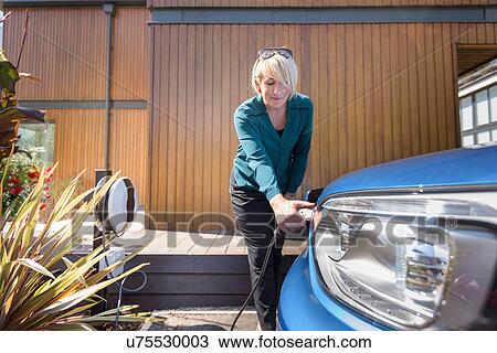 Woman charging electric car from charging point View Large Photo Image Stock Image - Woman charging electric car from charging point. Fotosearch