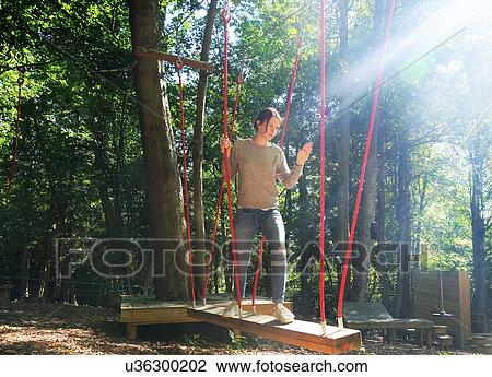 Woman crossing rope bridge on assault course View Large Photo Image Stock Image - Woman crossing rope bridge on assault course. Fotosearch
